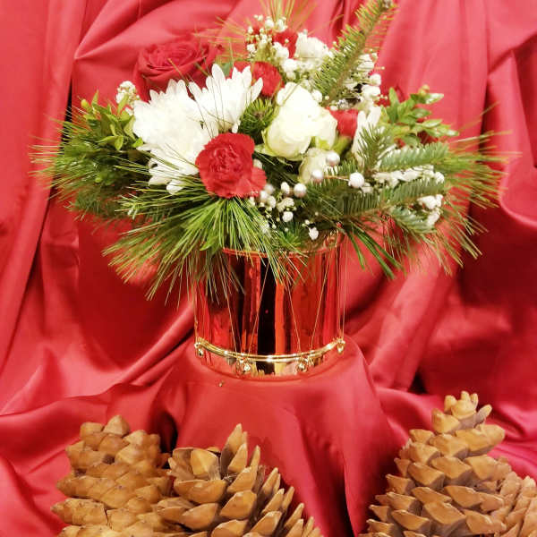 Red and white floral arrangement in a metallic vase with pinecones