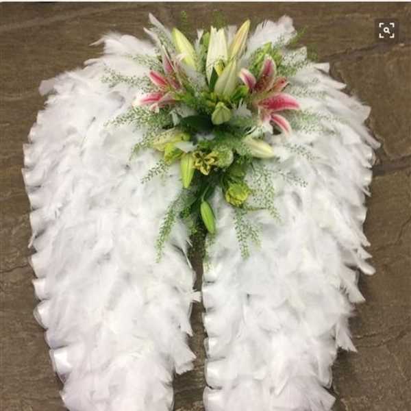 White feathered funeral spray with lilies and pink accents