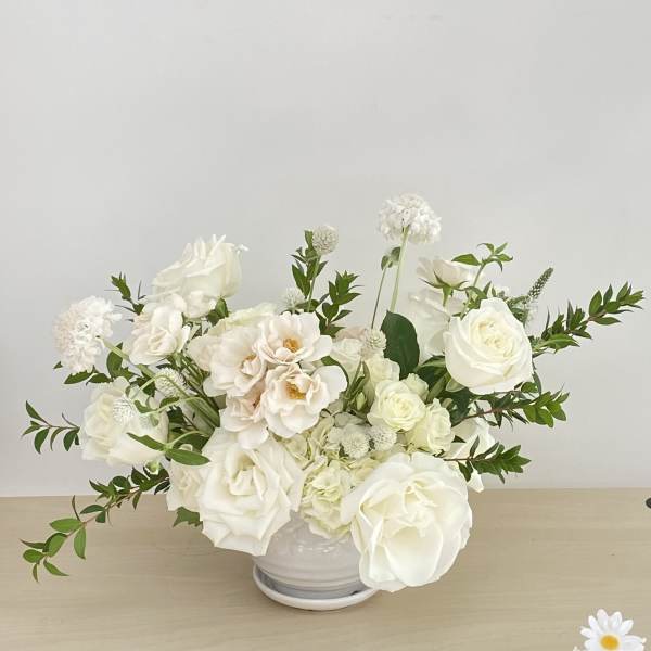 White rose arrangement in a white bowl vase