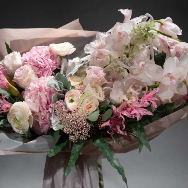 Large bouquet of pale pink and white flowers wrapped in blush paper