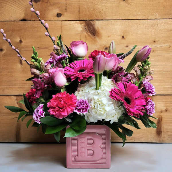 Pink and white mixed flower arrangement in a pink ceramic cube vase with the letter B on the front