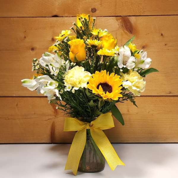 Yellow and white mixed bouquet in a glass vase with a yellow ribbon