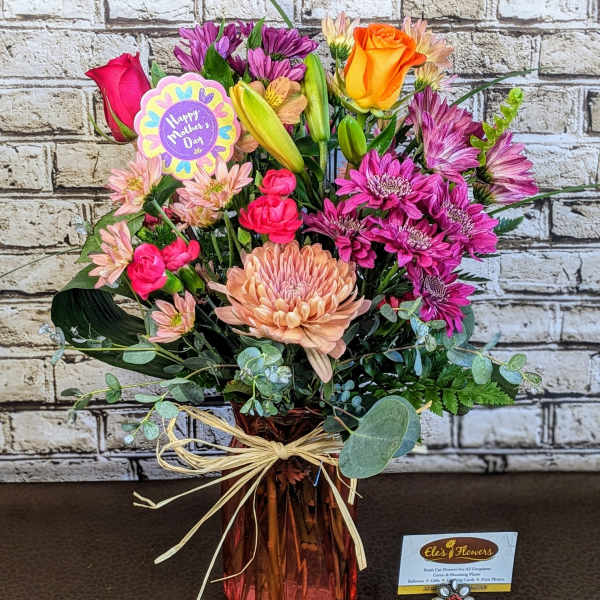 Mixed bouquet in a pink glass vase with roses and chrysanthemums