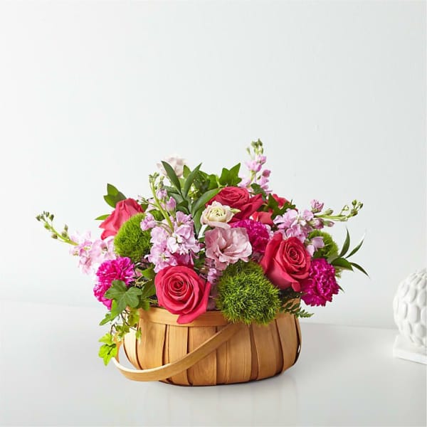 Basket arrangement of pink roses and purple flowers