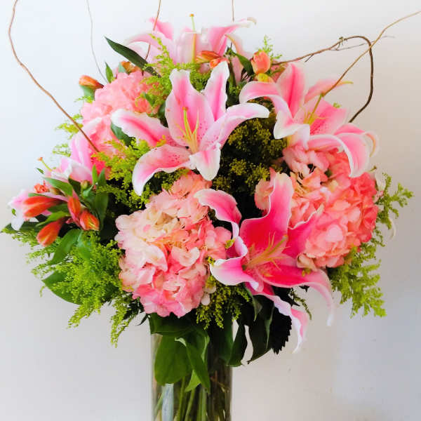 Pink lilies and hydrangeas arranged in a clear glass vase