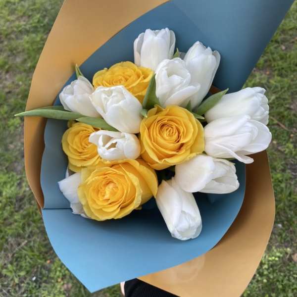 Bouquet of yellow roses and white tulips wrapped in blue and tan paper