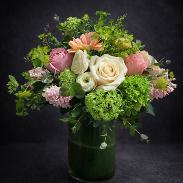 Mixed pink and cream flowers in a tall green vase
