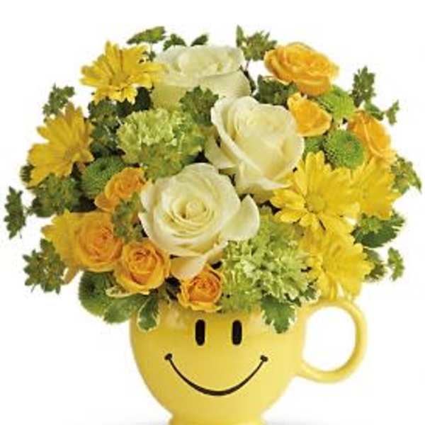 Yellow and white flower arrangement in a smiley-face mug