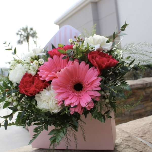 Pink gerbera daisies and red carnations in a pink box