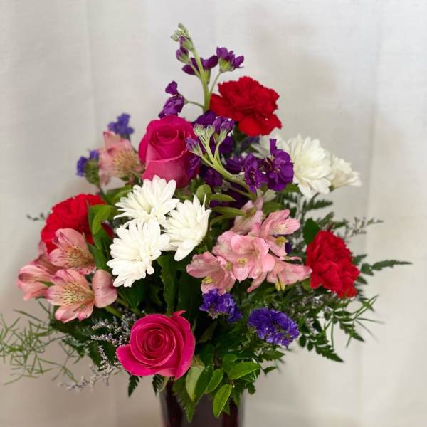 Mixed bouquet of pink, red, white, and purple flowers in a dark vase