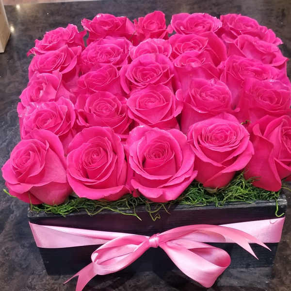 Pink roses arranged in a black box with a pink ribbon