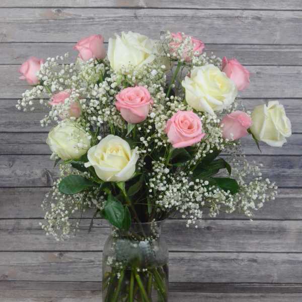 Pink and white roses arranged in a glass vase