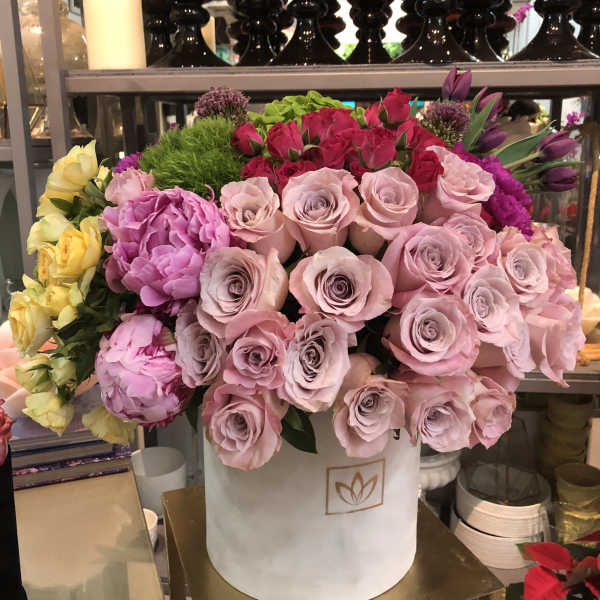 Mixed bouquet of pink and purple roses in a white hatbox
