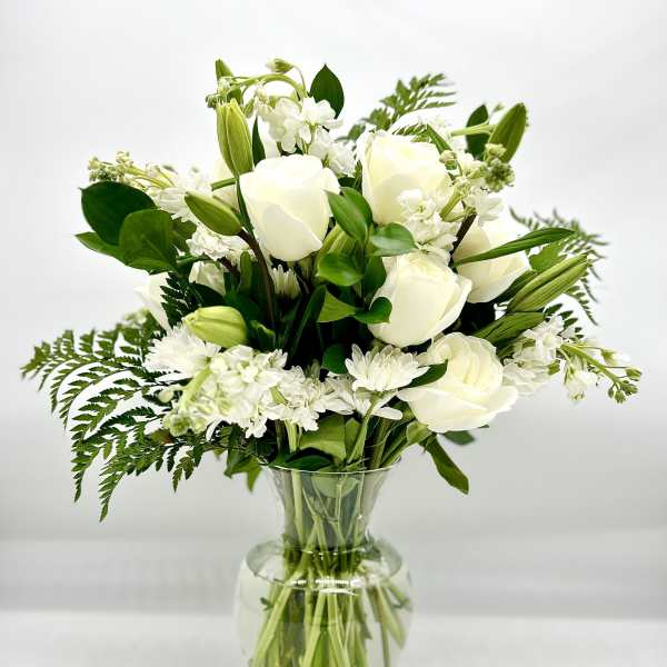 White roses and lilies arranged in a clear glass vase