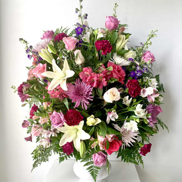 Large mixed bouquet of pink, white, and purple flowers in a white vase