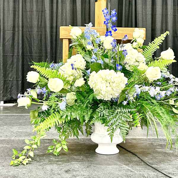 Large white and blue floral arrangement in a white urn