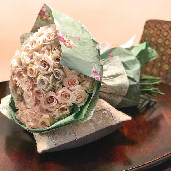 Bouquet of pale pink and cream roses wrapped in green paper