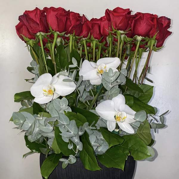 Red roses and white orchids arranged in a black vase