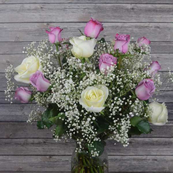 Pink and white roses in a glass vase with baby's breath