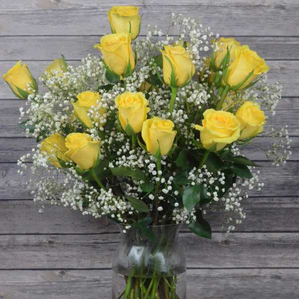 Yellow roses in a clear glass vase with white baby's breath