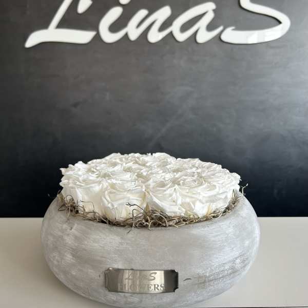 White roses arranged in a round gray container