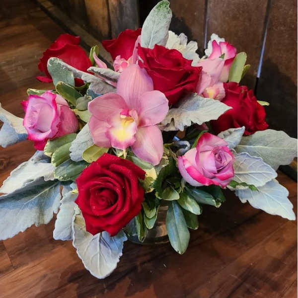 Bouquet of red and pink roses with a pink orchid in a glass vase
