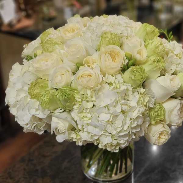White and pale green bouquet of roses and hydrangeas in a glass vase