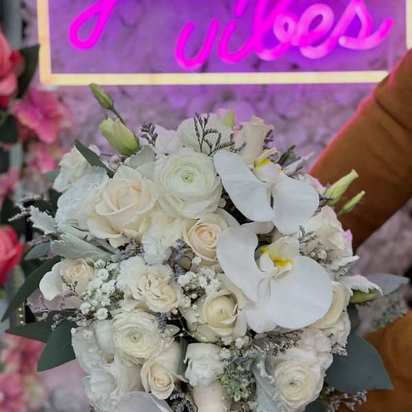 White bridal bouquet with roses, ranunculus, and orchids