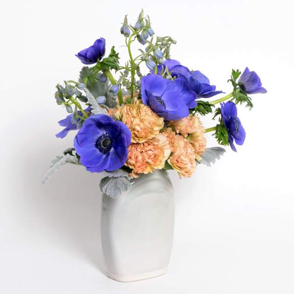 Blue and peach flowers arranged in a white vase