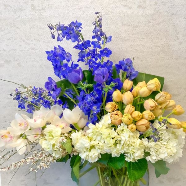 Mixed bouquet of blue, white, and yellow flowers in a glass vase