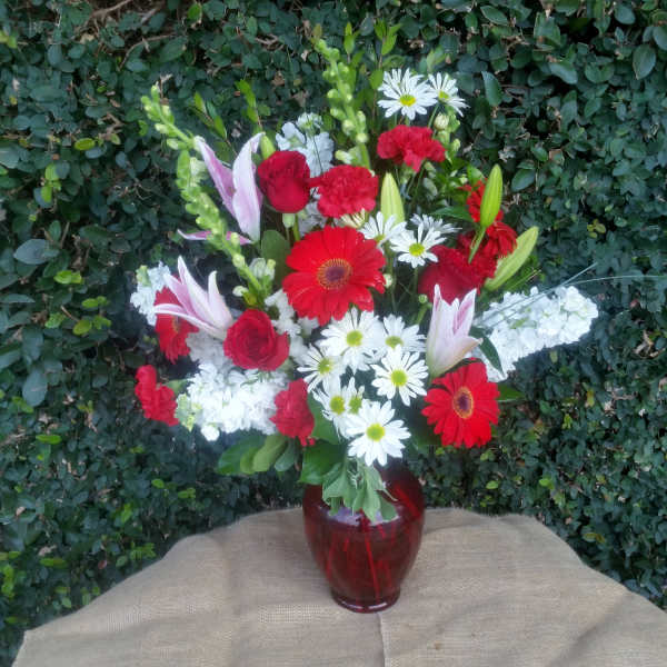 Mixed bouquet of red, white, and pink flowers in a red glass vase