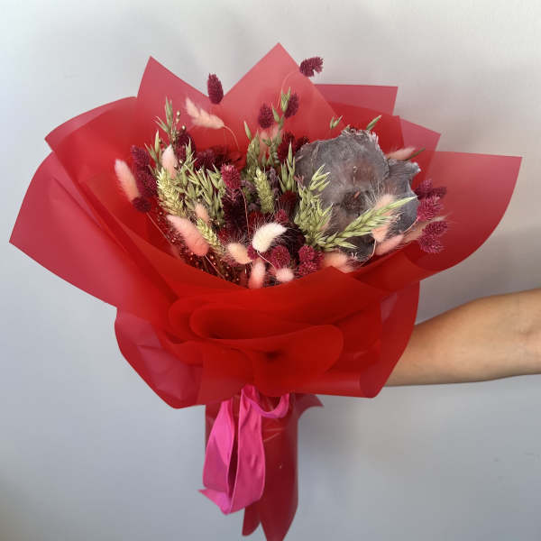 Bouquet of dried flowers wrapped in red paper with a pink ribbon