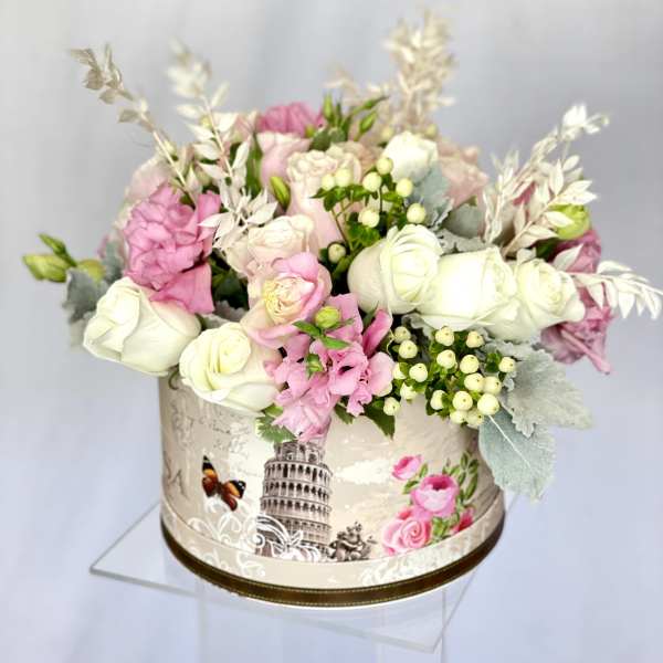 Pink and white roses arranged in a decorative round box