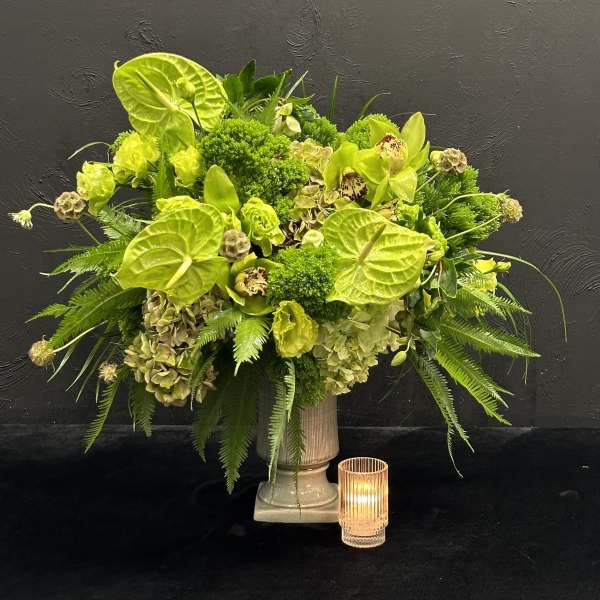 Lime green floral arrangement in a pedestal vase with a small candle