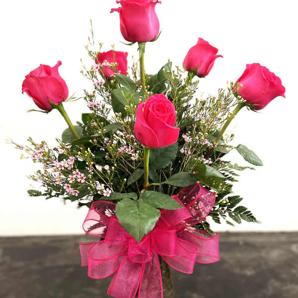 Pink rose bouquet in a glass vase with a pink ribbon bow