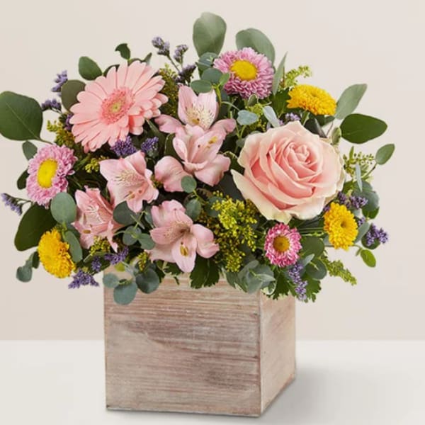 Mixed pink and yellow flowers in a wooden box