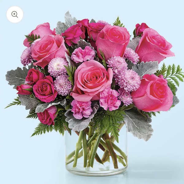 Pink roses and small lavender blooms in a clear glass vase