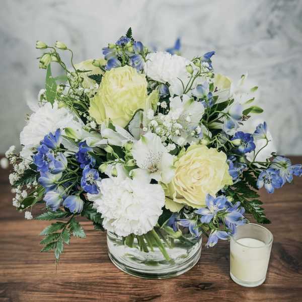 Bouquet of pale yellow and white flowers in a clear glass bowl vase