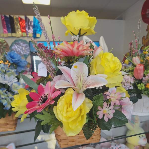 Mixed bouquet in a woven basket with yellow, pink, and white flowers