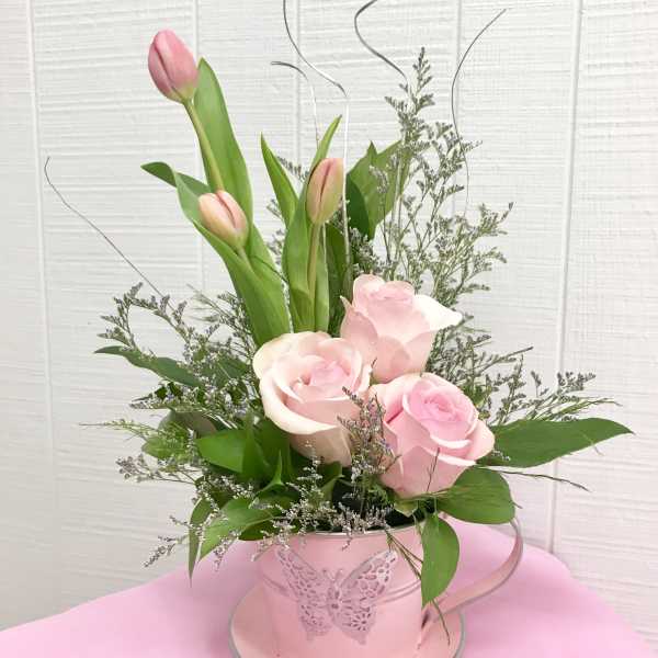 Pink tulips and roses arranged in a pink butterfly tin