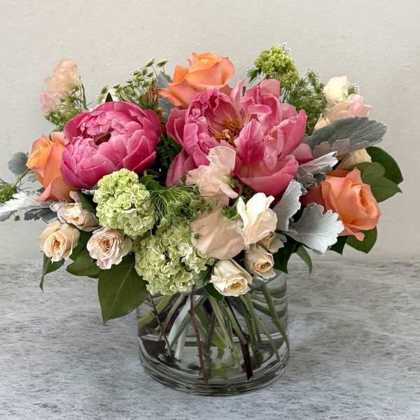 Mixed pink and peach flower arrangement in a clear glass vase