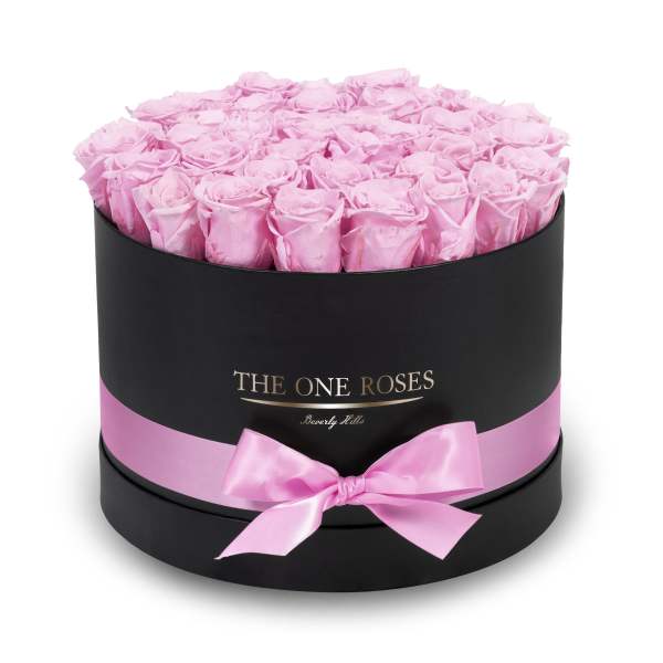 Round box filled with pink roses and tied with a pink ribbon