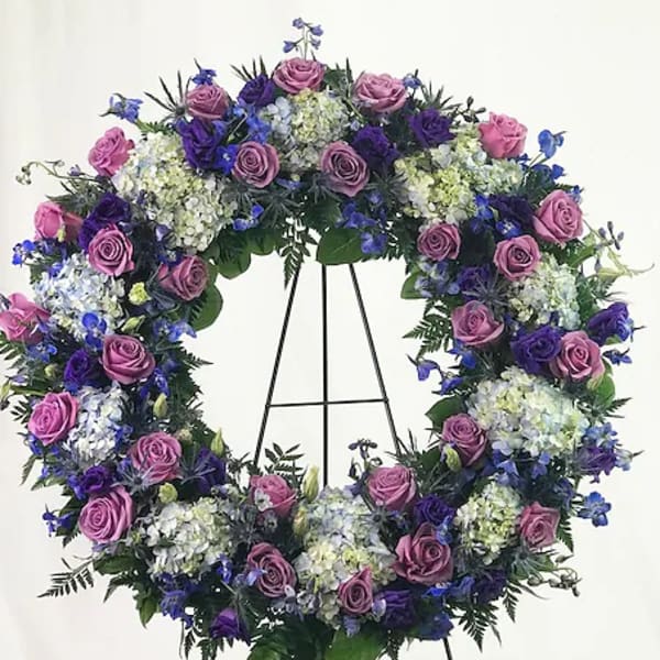 Purple and blue floral wreath on a black stand