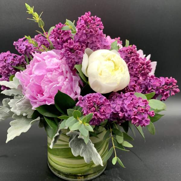 Pink and white flowers arranged in a glass vase with purple blooms