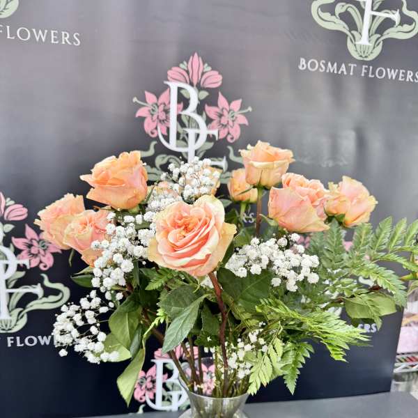 Peach roses with baby's breath in a clear glass vase