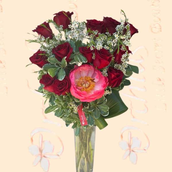 Bouquet of red roses and a pink peony in a tall glass vase