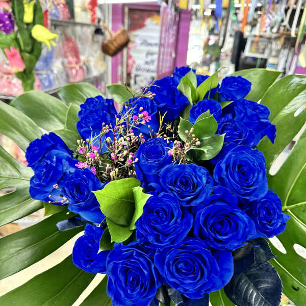 Bouquet of vivid blue roses with large tropical leaves