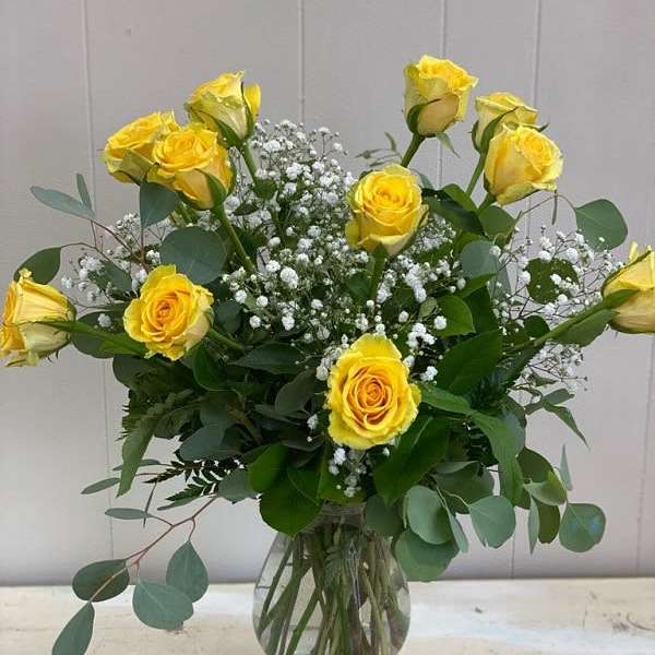 Yellow roses in a clear glass vase with white baby's breath