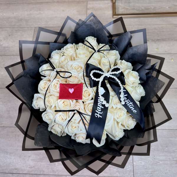 Bouquet of white roses wrapped in black paper with ribbon bows