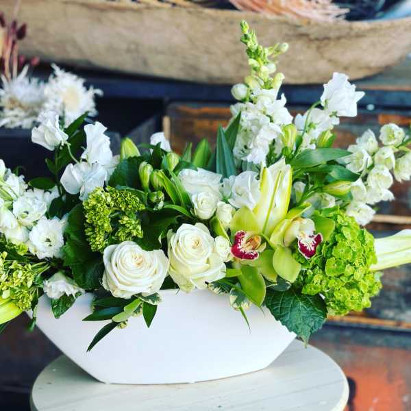 White and green floral arrangement in a white bowl vase